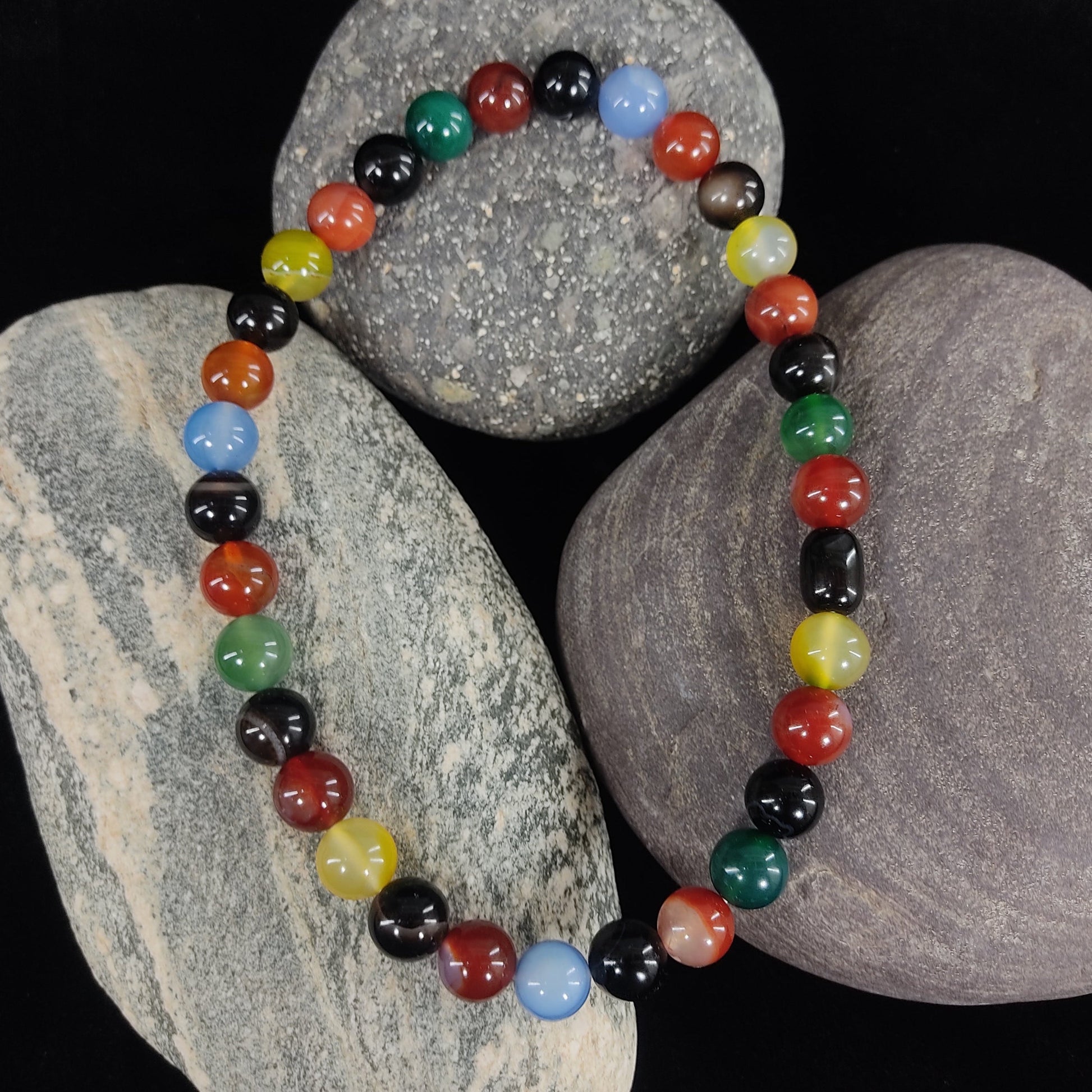 Colorful beaded bracelet on a dark background with stones